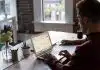 man operating laptop on top of table