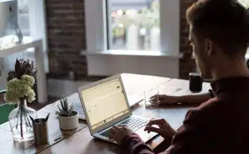 man operating laptop on top of table