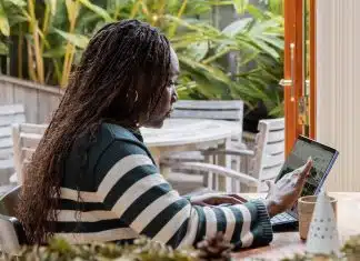 a person standing in front of a laptop computer talking on a cell phone