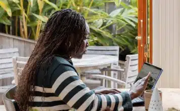 a person standing in front of a laptop computer talking on a cell phone