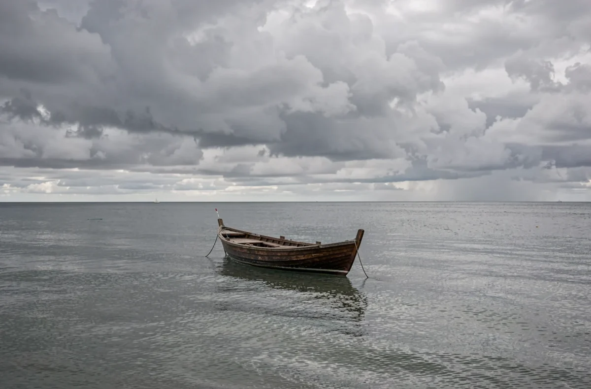 Petit bateau sur une mer calme sous un ciel chargé de nuages